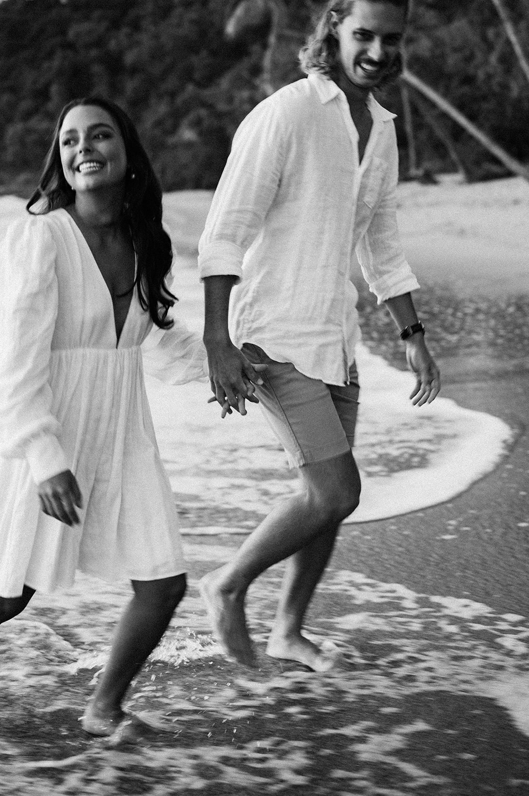 black and white photo with grain on couple having engagement session on beach