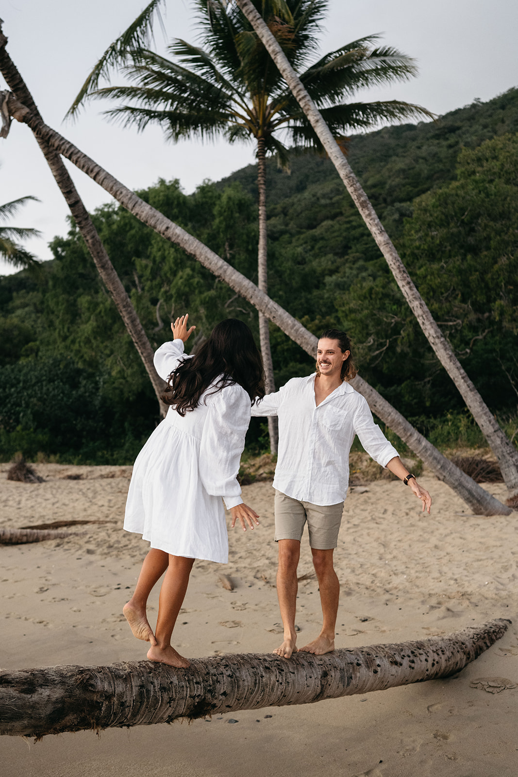 couple playing on palm tree during engagement session