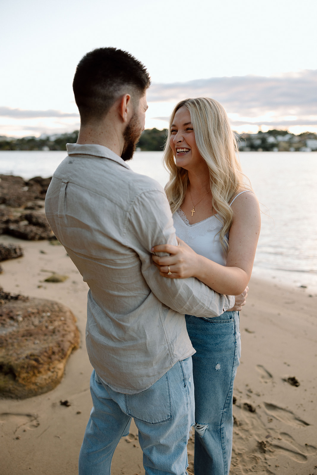 Couple laughing at each other at their beach engagement shoot
