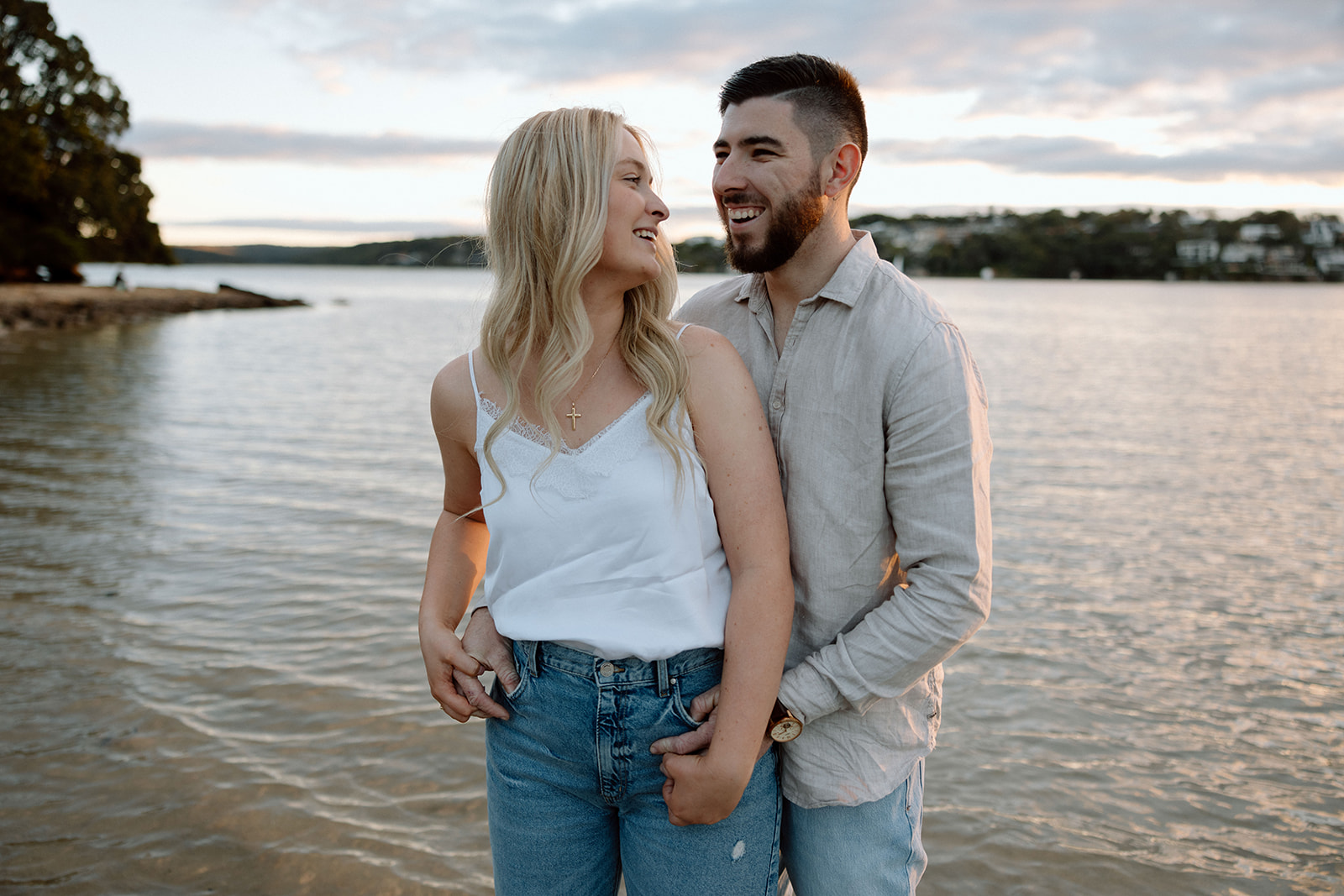 Couple laughing at each other at their beach engagement shoot