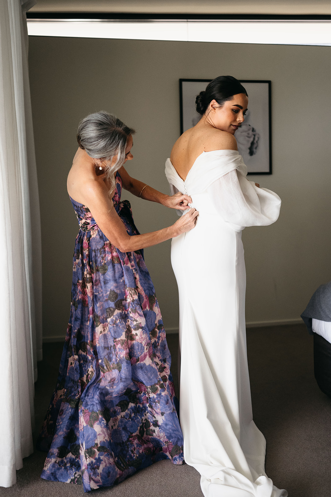 bride getting in dress with the help from mum