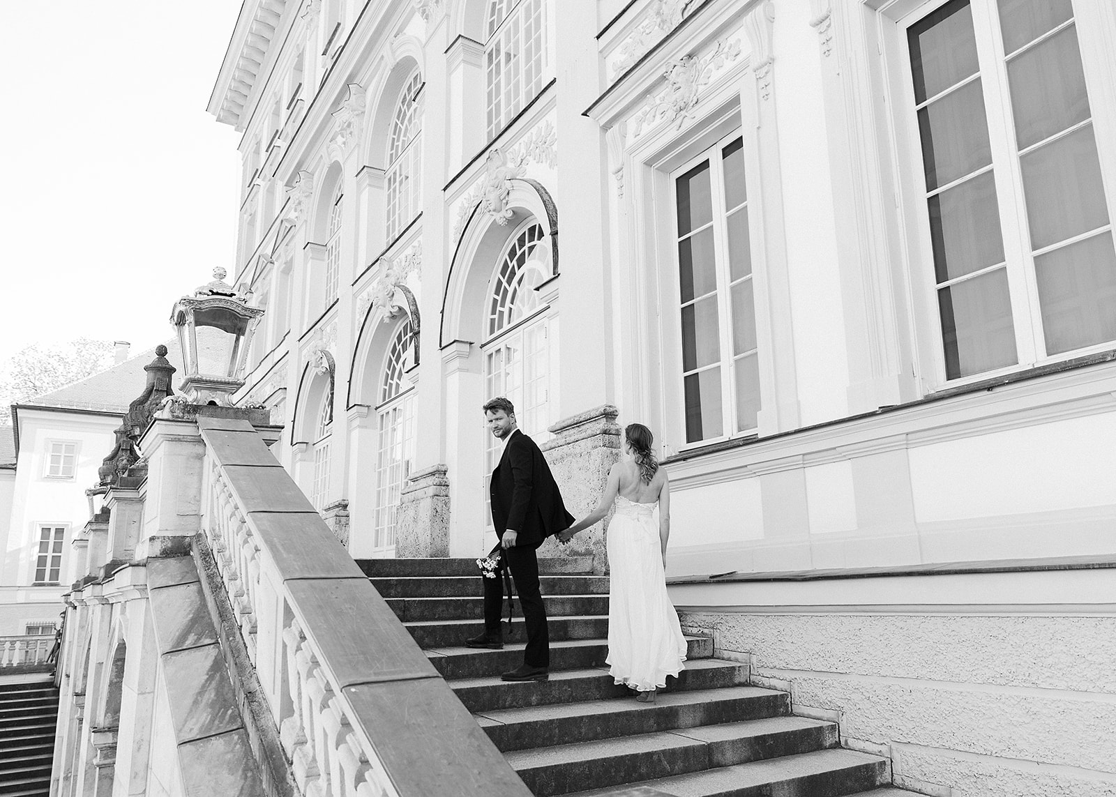 Bride and groom walk up the stairs of the castle for their wedding portraits at Schloss Nypmhenburg