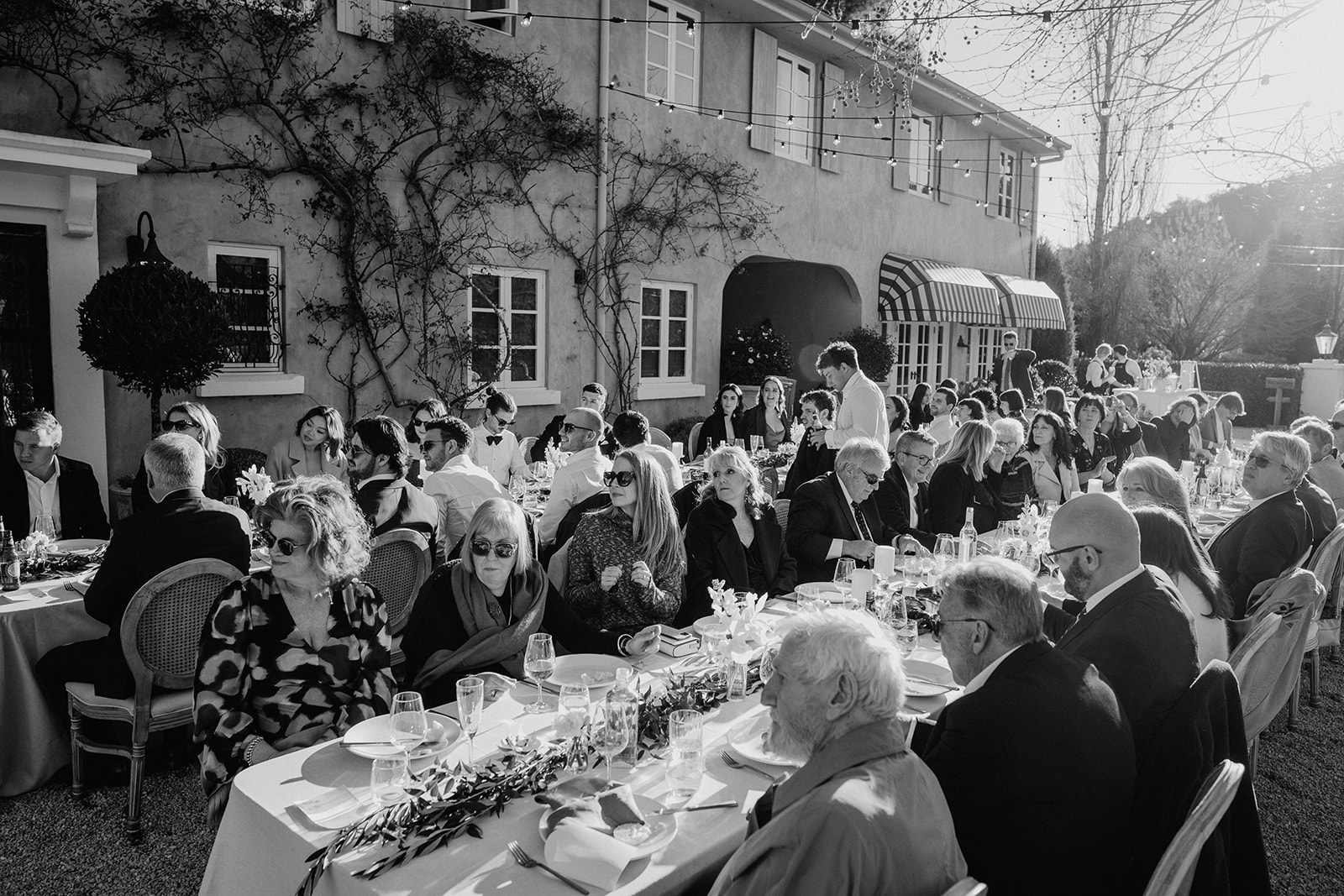 Redleaf wedding black and white of guests seated during reception backlit by sun