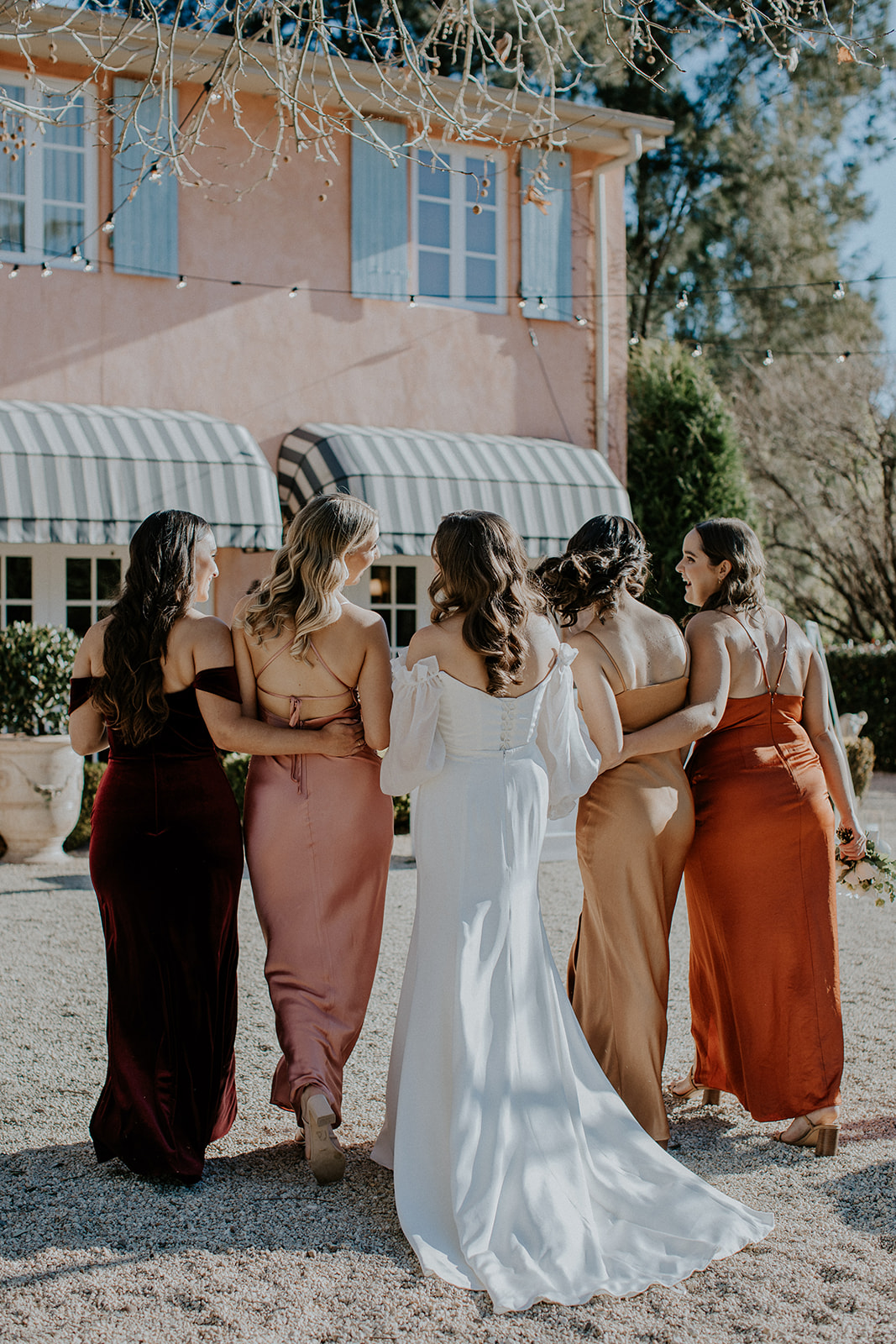 Redleaf wedding bride and bridesmaids link arms with backs to camera
