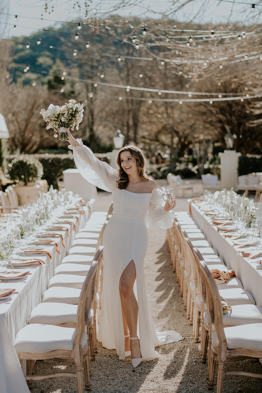 Redleaf wedding bride poses in front of outdoor reception with bouquet in air