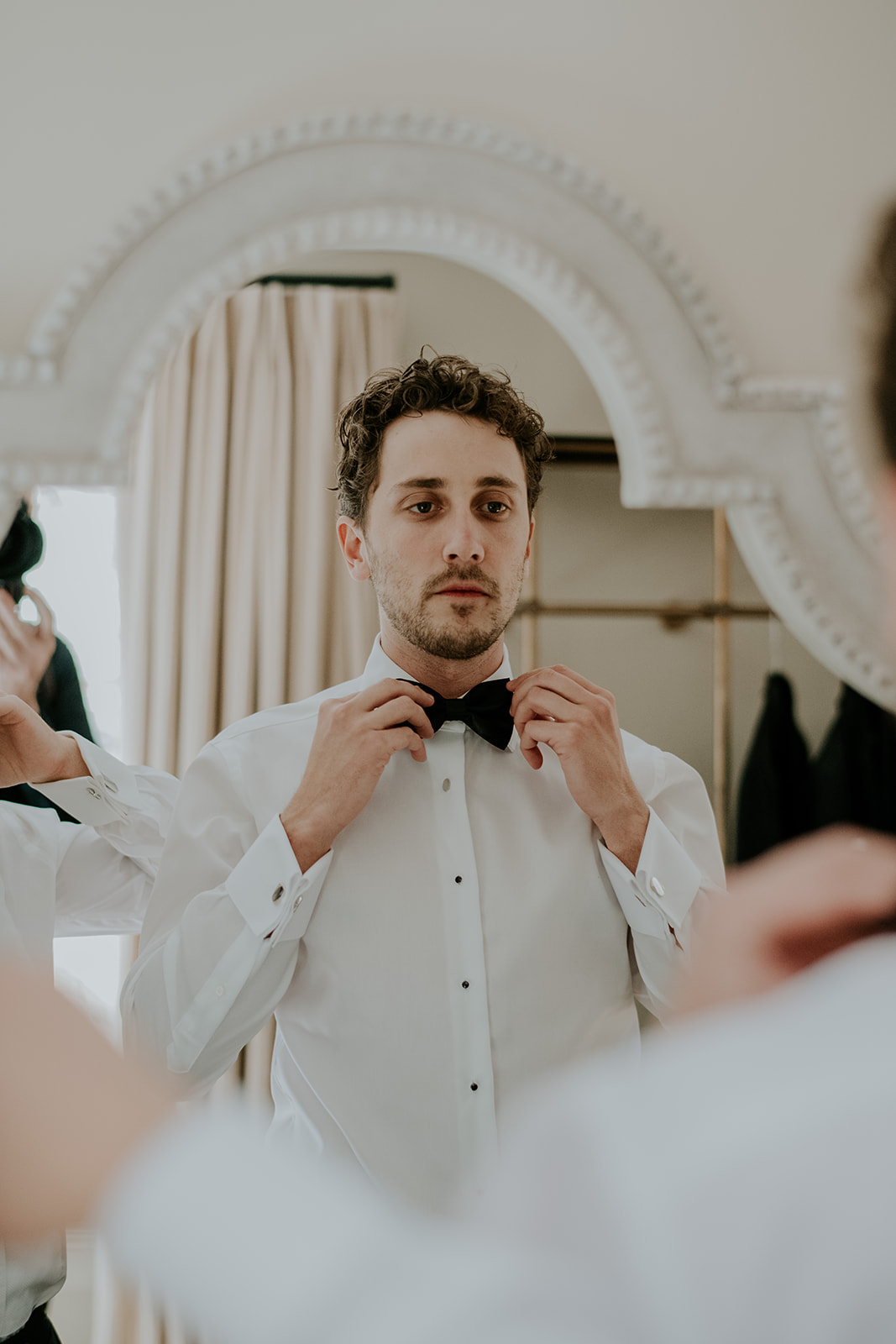 Redleaf wedding groom adjusts bow tie in mirror