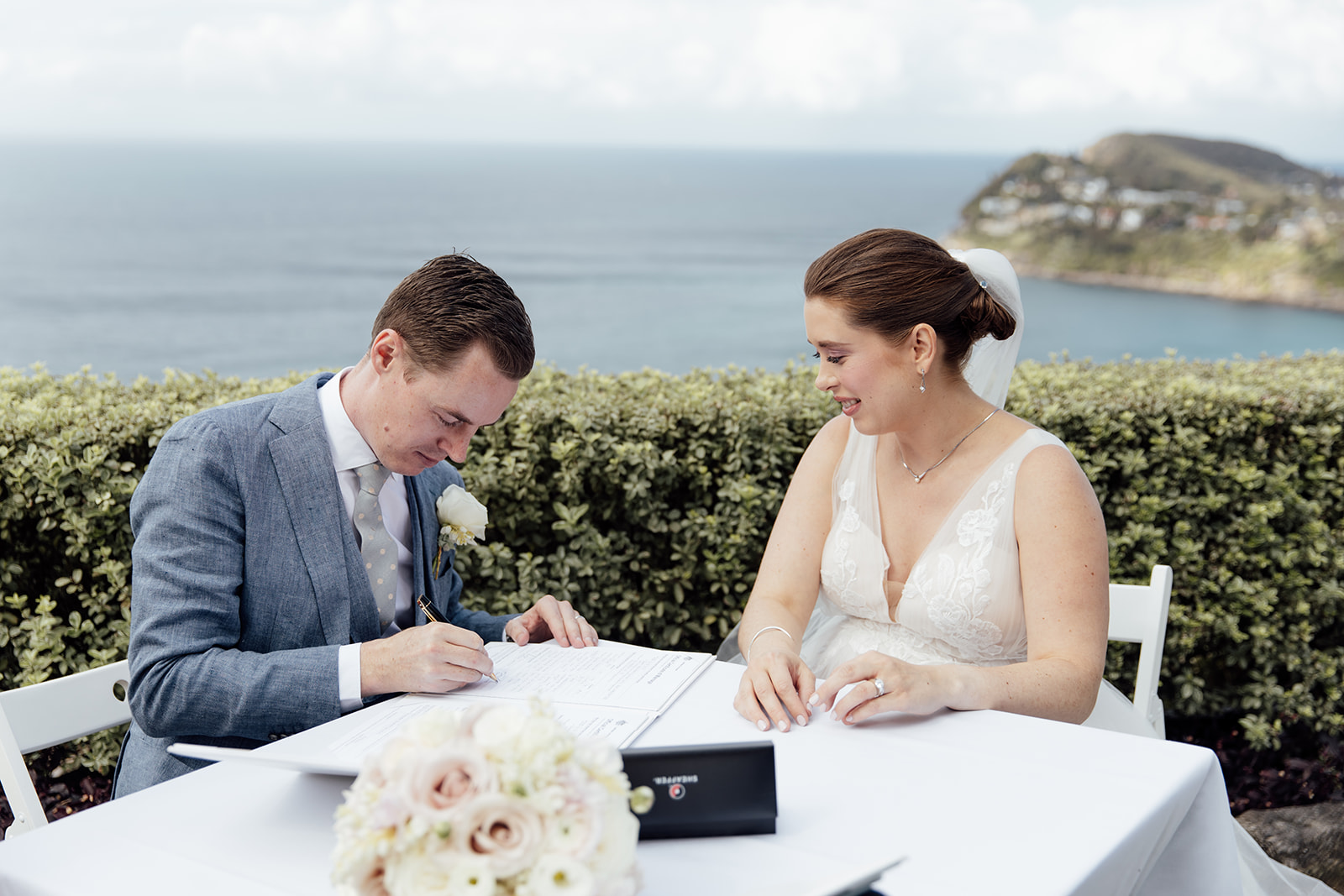 A couple signing their register with beach views behind them