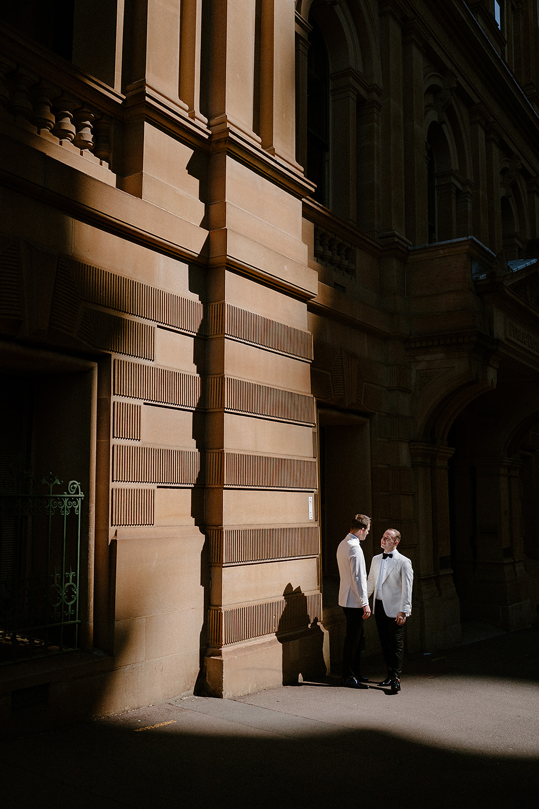 A same sex couple posing in nice city light for their Sydney Mint wedding.