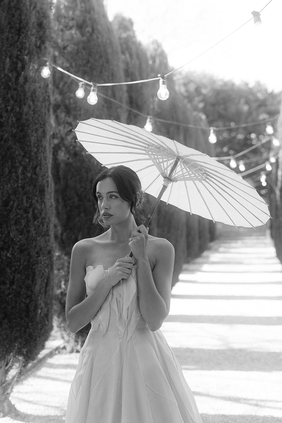 Black and white photo of bride with parasol at Mandalay House wearing Paolo Sebastian