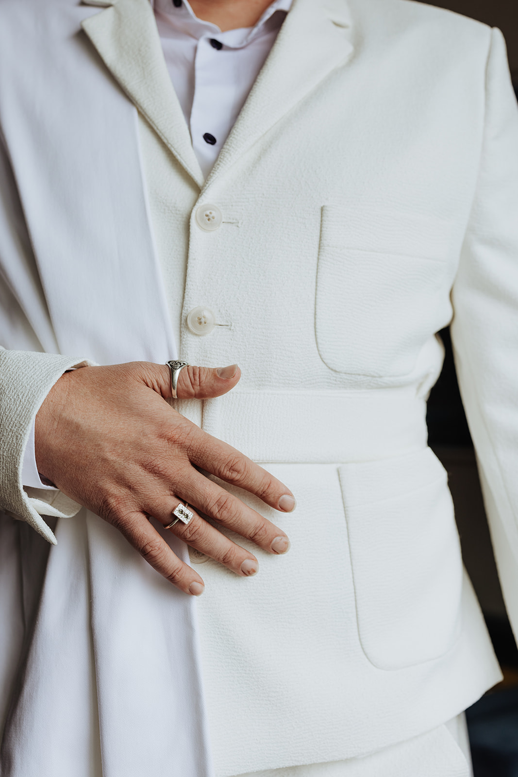 close up of grooms ring details against a white suit