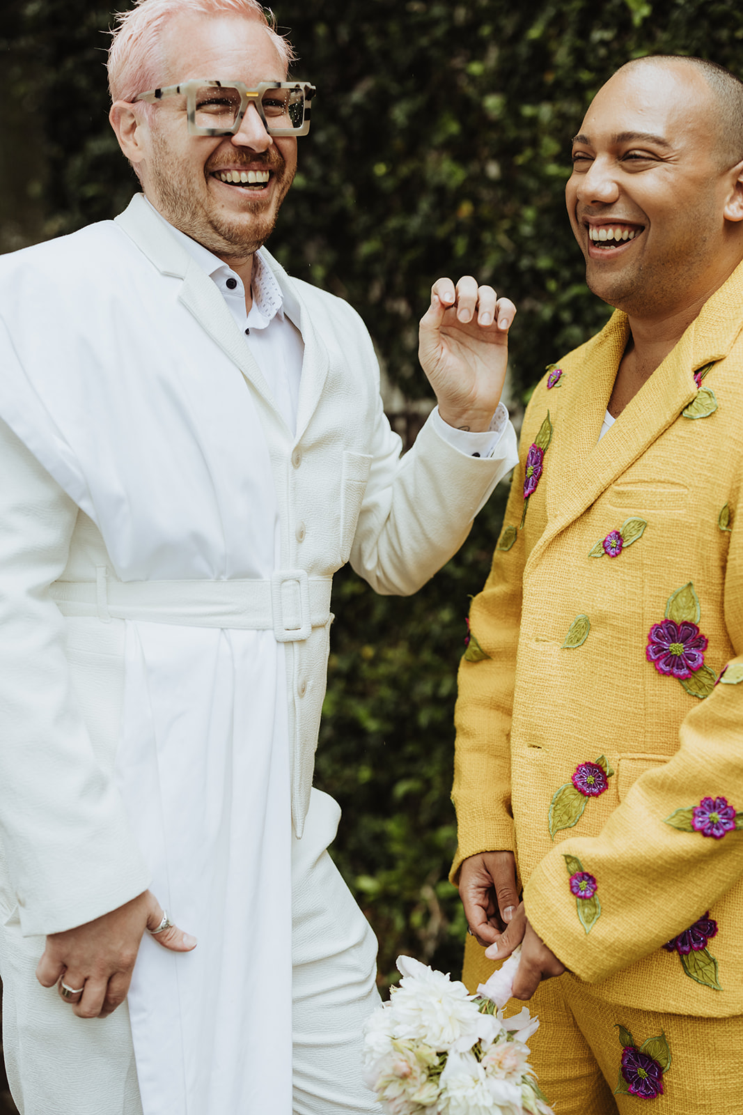 two grooms in suits laughing on their wedding day