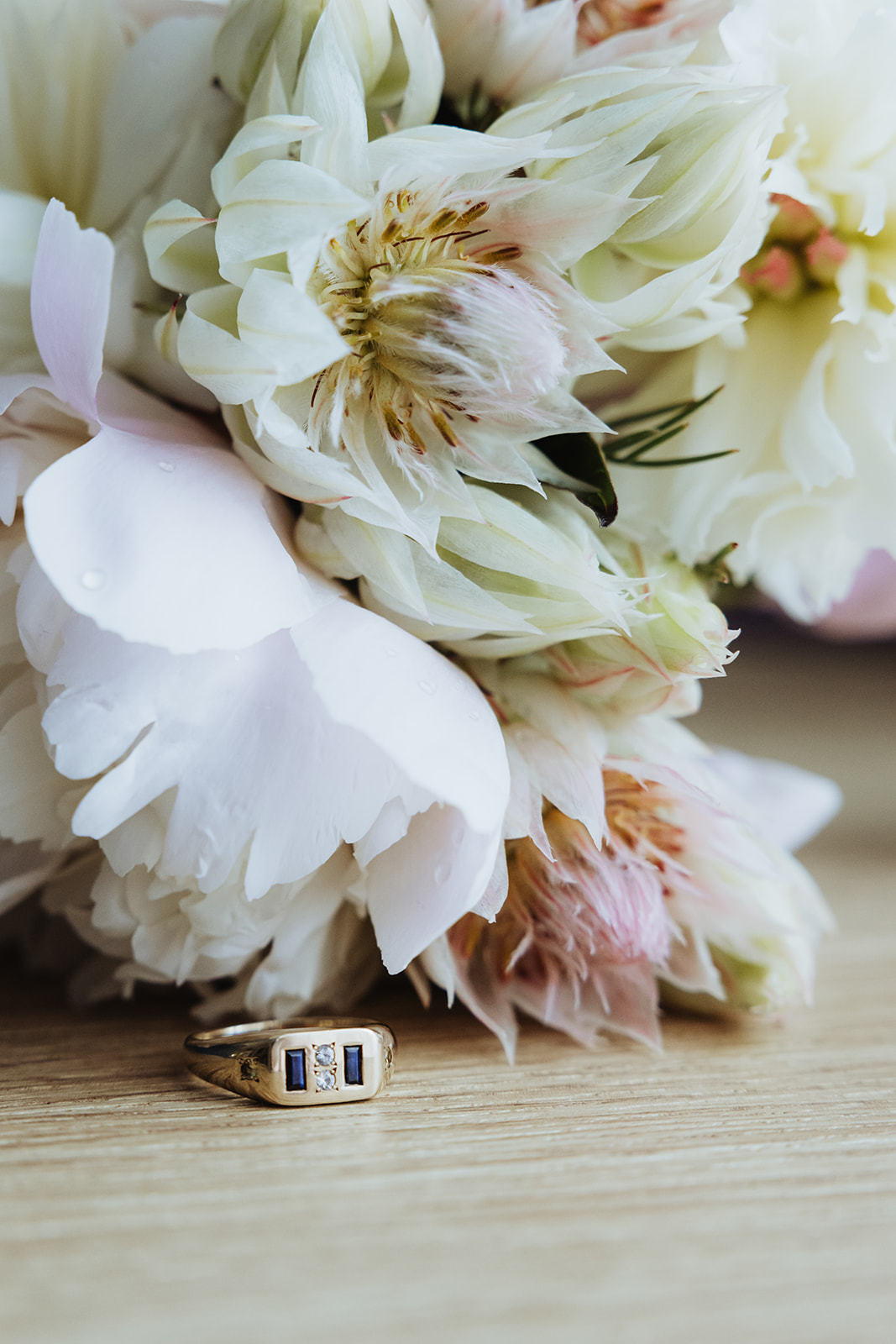 white bridal bouquet with a gold band grooms ring