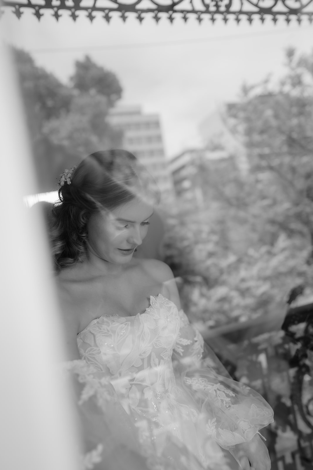 Bride radiant in flowing wedding dress, captured through window.