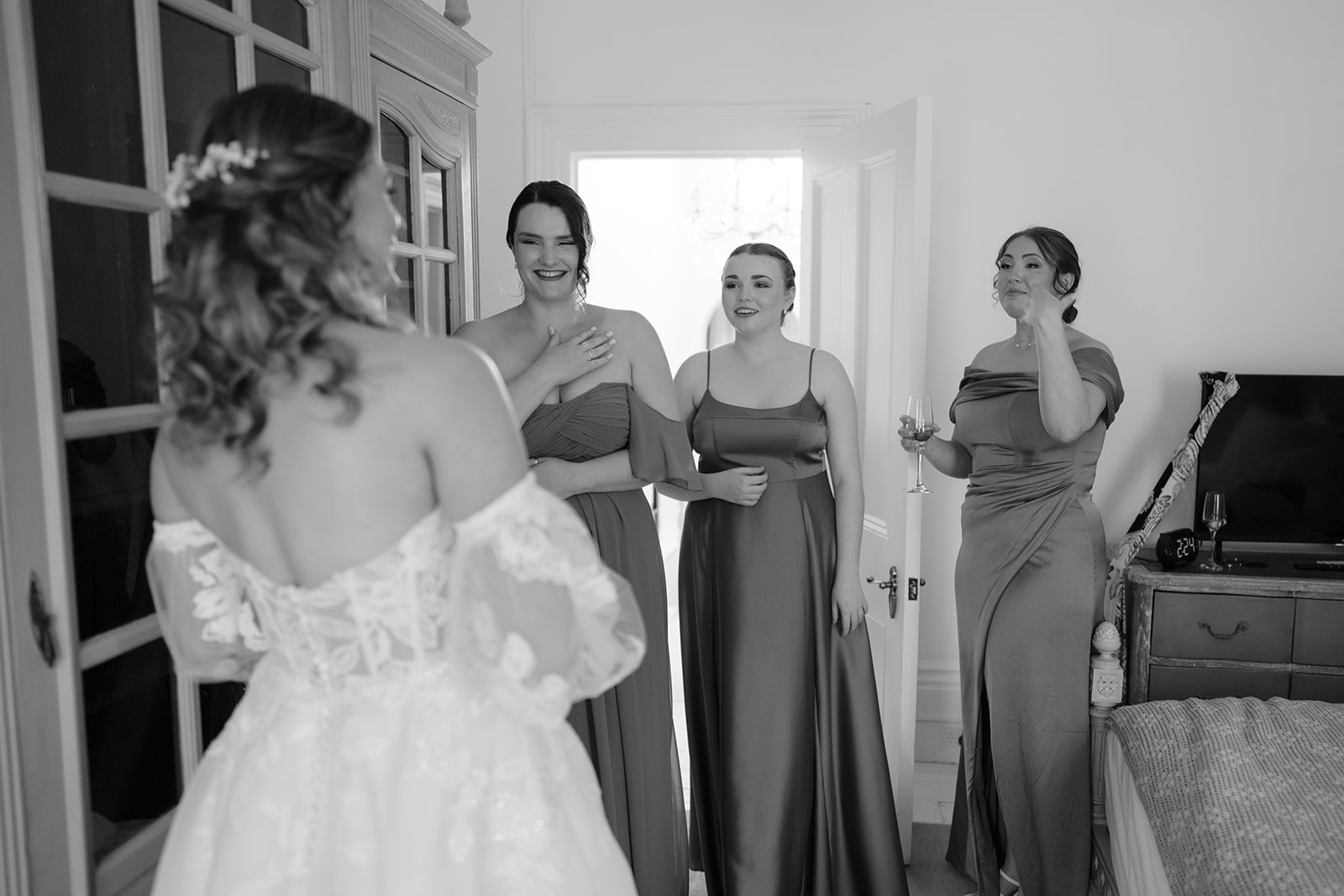 Bride revealing stunning wedding dress to excited bridesmaids
