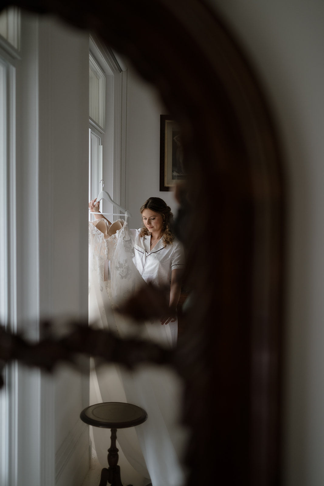Intimate portrait of bride holding her dress, reflected in mirror, capturing the emotional build-up to her 