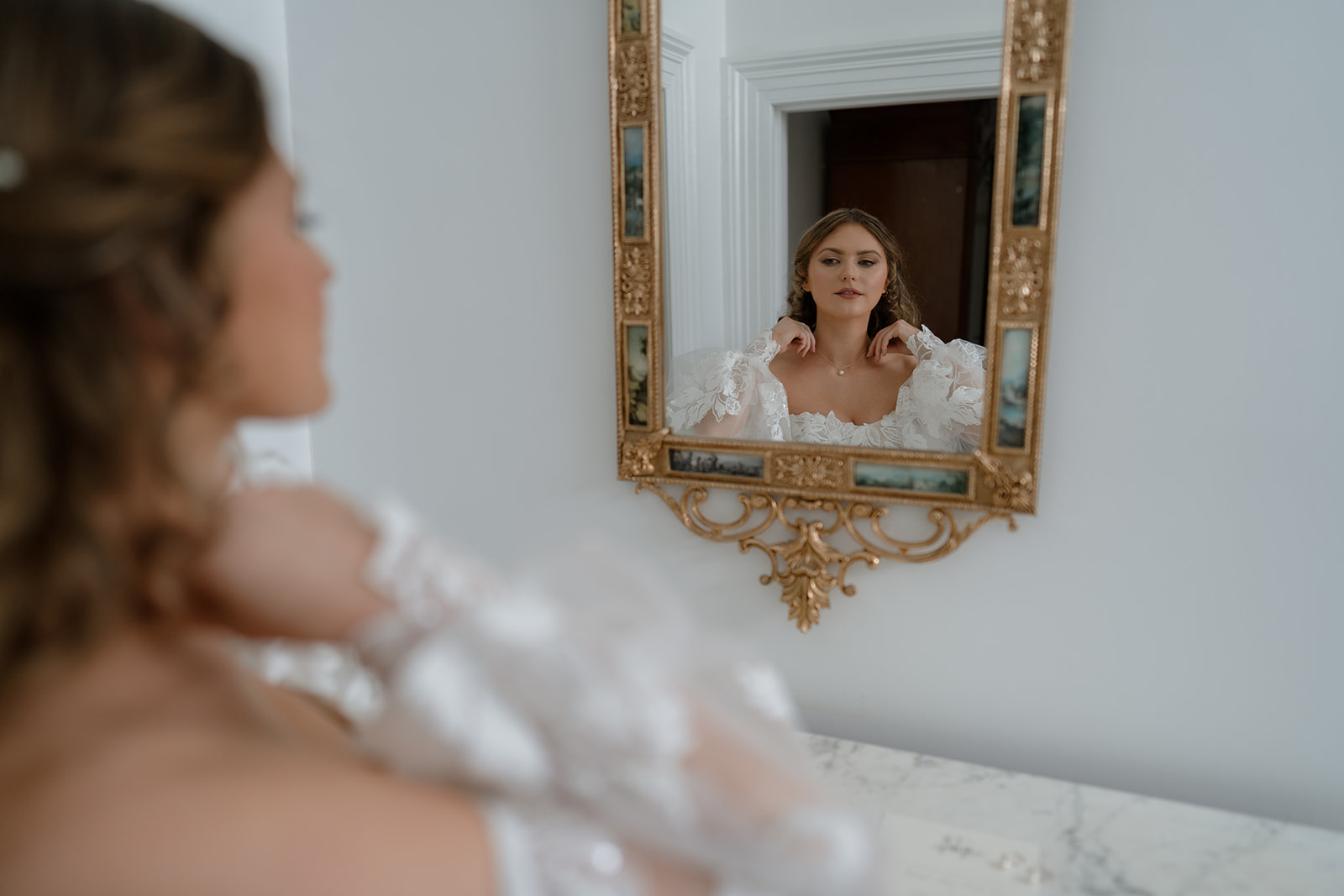 Wedding preparation: Bride adorns herself with a necklace while gazing into the mirror.