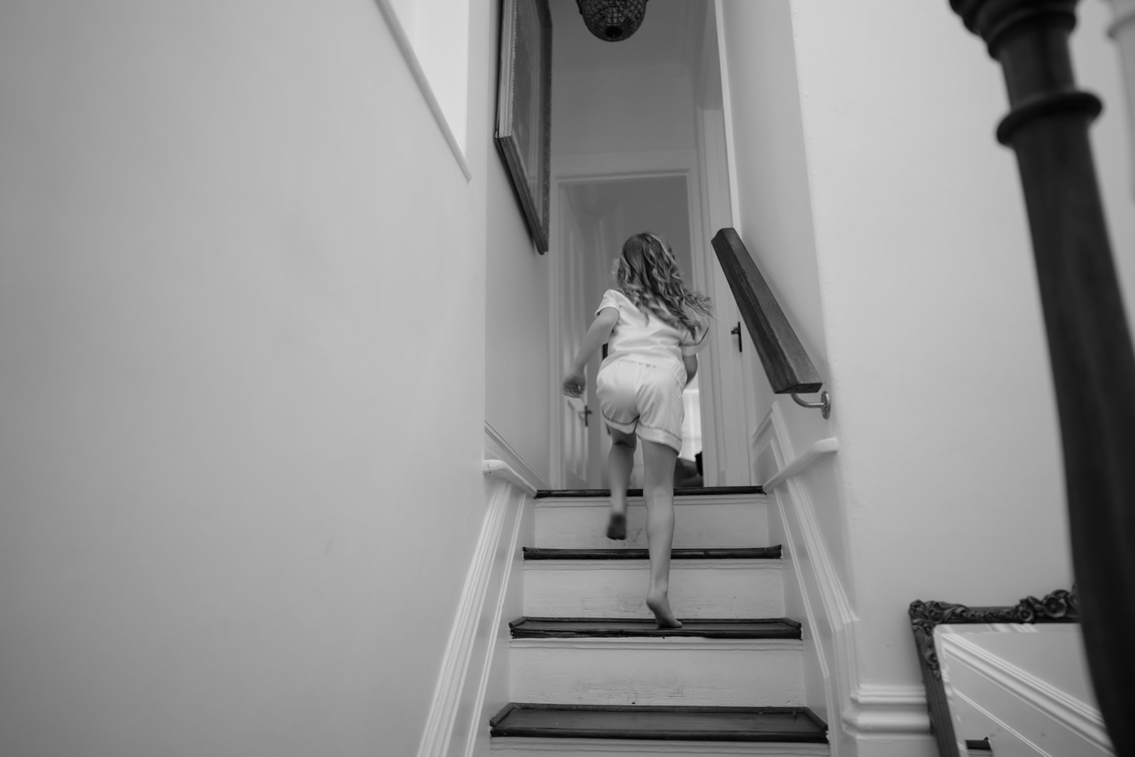 Young flower girl, filled with joy, runs up the staircase