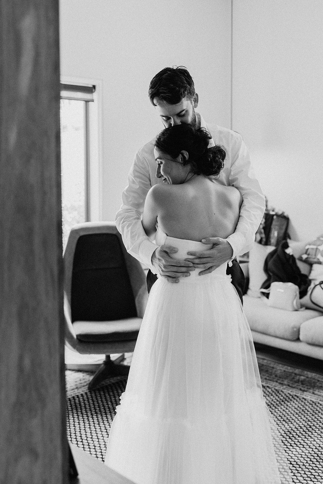 bride and groom have a hug in the lounge room while getting ready