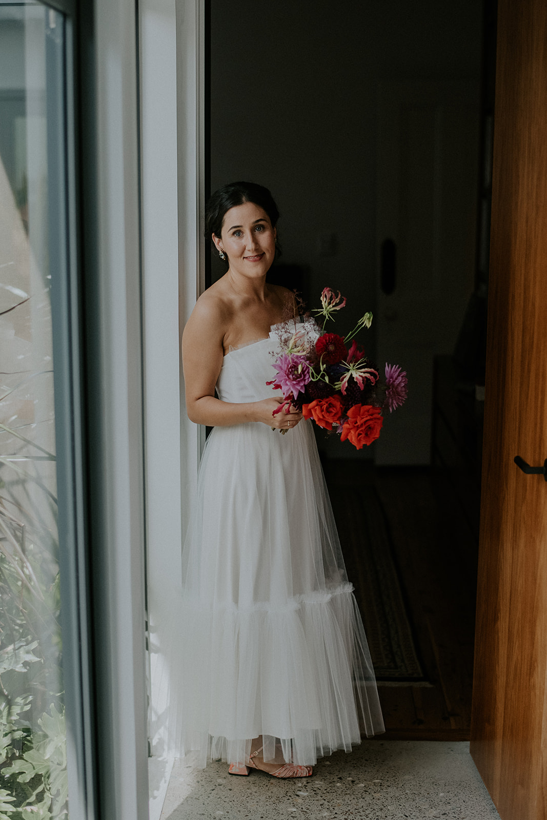 portrait of bride holding bouquet in soft window light