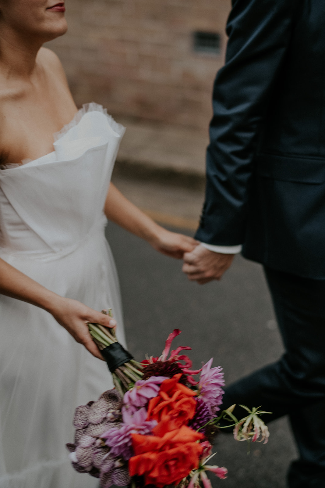 Scott Surplice bride and groom hold hands with bouquet in other hand
