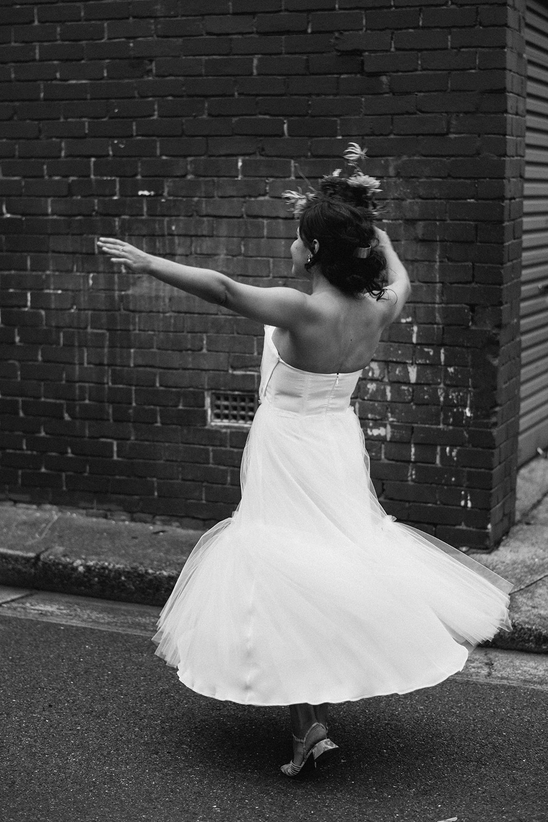 Scott Surplice portrait of bride in front of dark brick wall as she spins