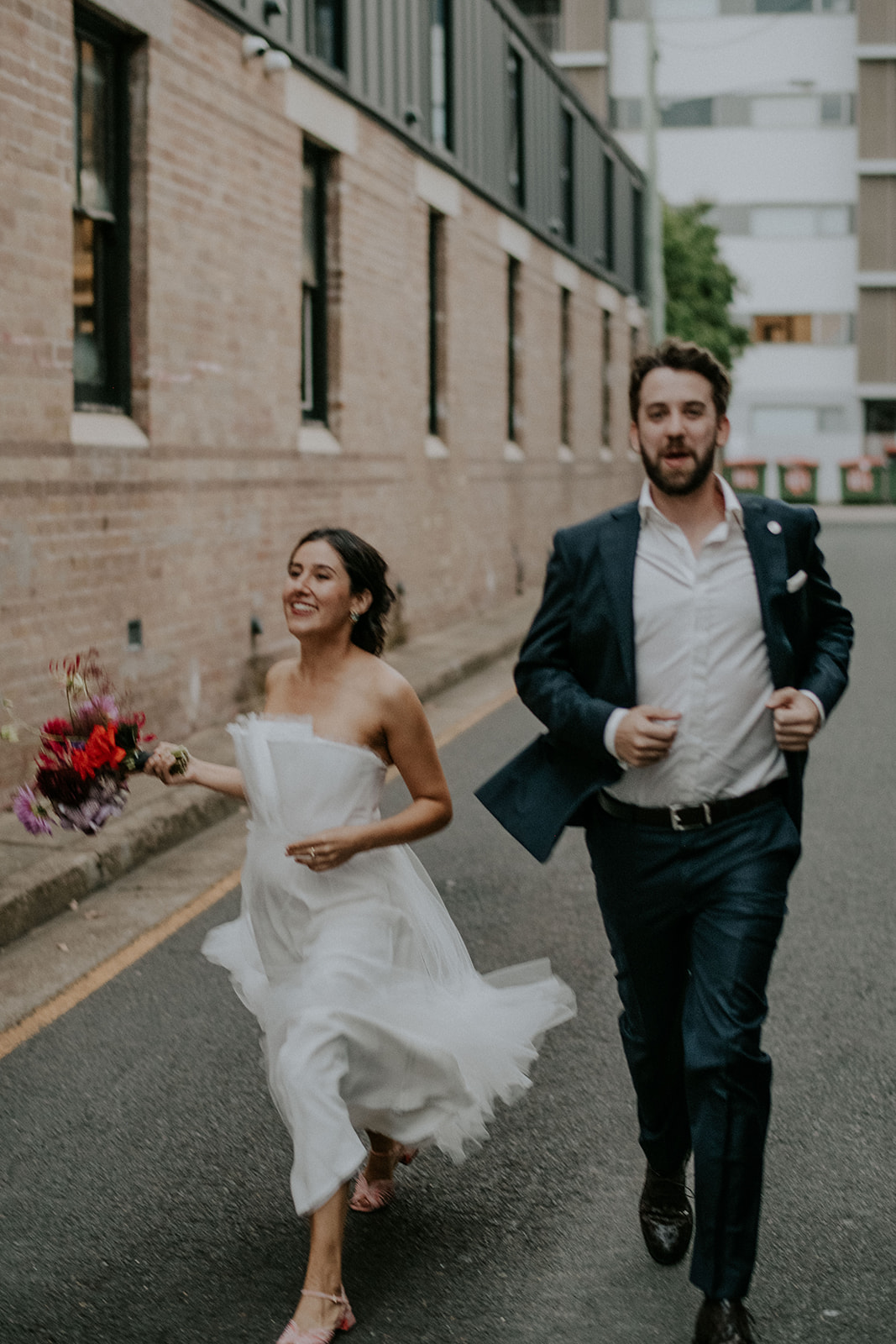 Scott Surplice portrait of bride and groom as they run in alley